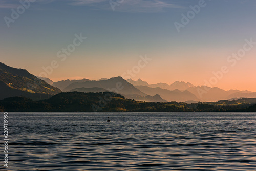 The Swiss lake Zugersee (Zug Lake) with the alps mountain layer in the distance  at the sunset  golden hour time