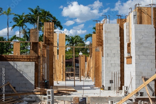 Residential house structure under development featuring masonry concrete blocks, wooden shuttering, and tropical palm trees