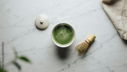 Top View of Freshly Prepared Warm Matcha Green Tea in a Ceramic Bowl with a Traditional Bamboo Whisk on a Marble Tabletop