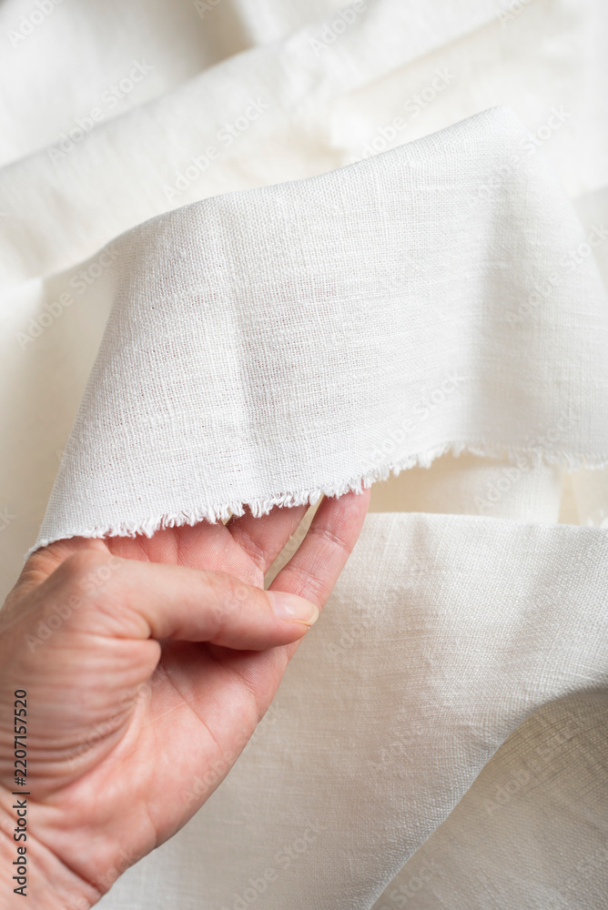 Fototapeta premium Hand Holding Off White Linen Fabric Edge