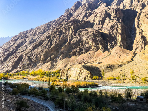 A scenic mountain pass in the Hindu Kush, where a winding river flows through the golden autumn landscape of the Wakhan Valley