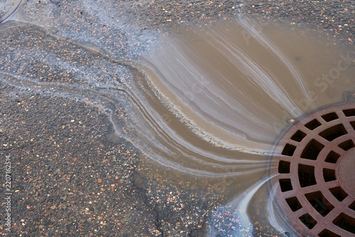 Drain With Water and Debris on a City Street After Rainfall