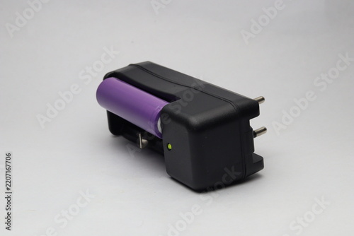 Portable lithium ion battery charger with cell inserted and LED indicator light on white background