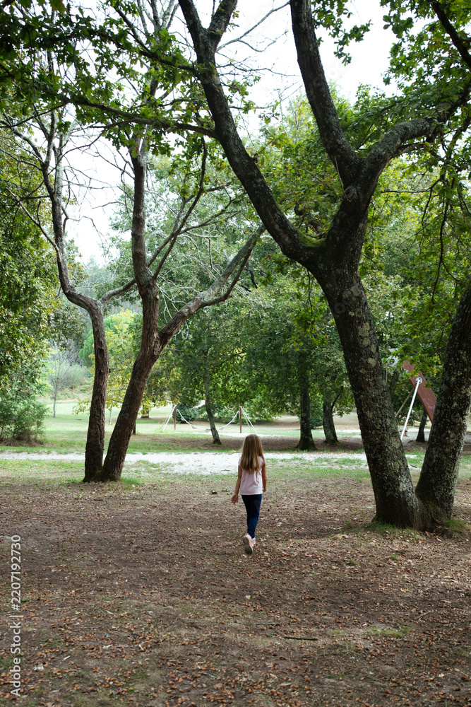 Fototapeta premium Young girl walking through natural park exploring outdoors