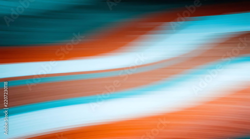 Abstract motion blur of orange and teal stripes across a white background suggesting speed and dynamism