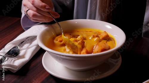 Hand stirring creamy soup with croutons at a restaurant table