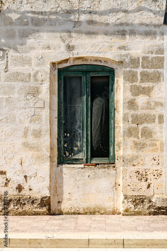 Rustic green wooden window set in an ancient weathered limestone wall, Italy