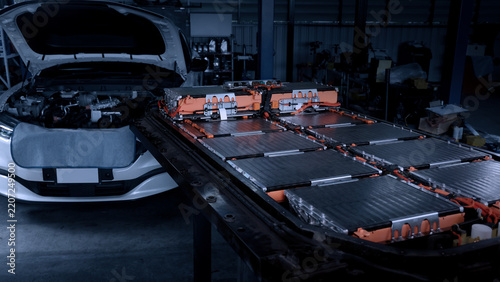 EV car service. Electric vehicle battery pack being serviced or inspected in automotive workshop. Large battery modules and high voltage components. Modern EV power systems. Lithium ion NMC NCA or LFP