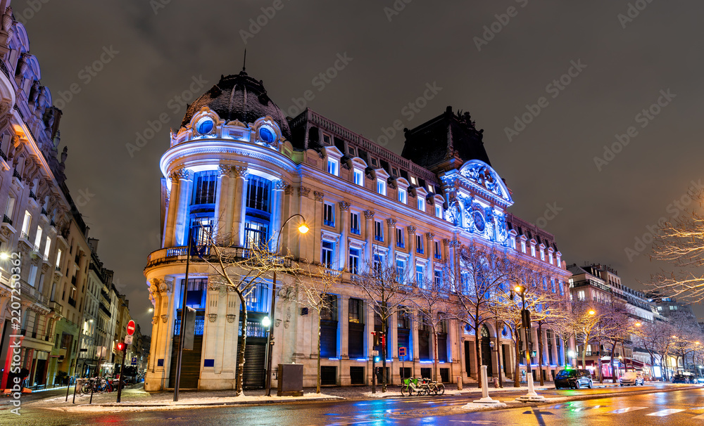 Obraz premium Historic neoclassical architecture on Boulevard des Italiens illuminated at night in Paris, France.