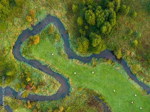 Aerial view of a winding Rawka River meander surrounded by meadows and autumn vegetation near Bolimów, Poland