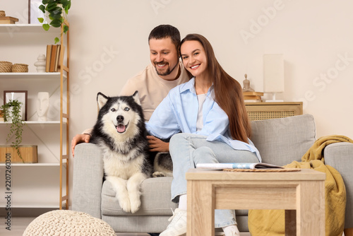Pet ownership and family lifestyle, happy couple sitting on a sofa with their...