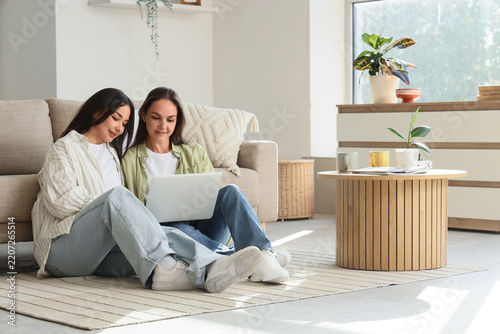 Remote work and collaboration, two women using a laptop together at home for ...