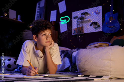 Remote learning and homework stress, thoughtful boy studying in bedroom at ni...
