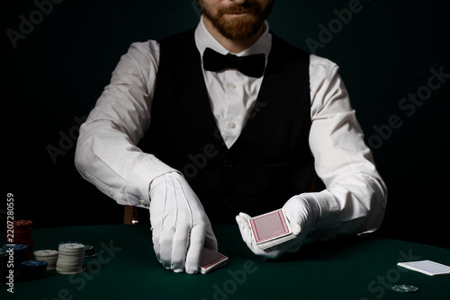 Fotografie Casino gambling and professional gaming, dealer in tuxedo and white gloves shuff