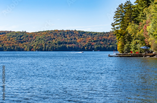 Autumn Scene on a Lake with Colorful Foliage and People Lounging on the Docks and Crusing on Motorboats