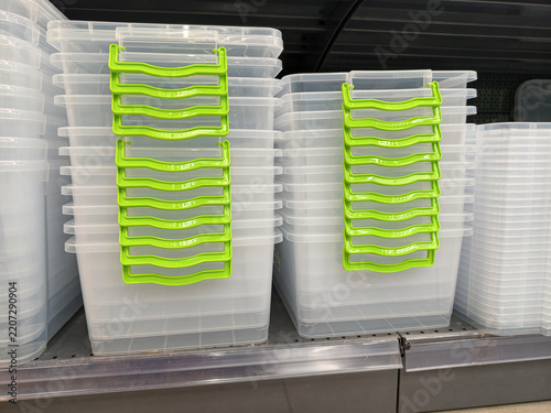 Canvastavla Stacked white plastic containers for food storage with green handles on supermar