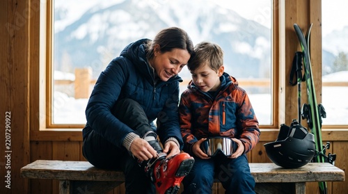 Parent helping a child fasten ski boots in a mountain lodge before skiing, family ski vacation and winter sports preparation at a snowy alpine resort