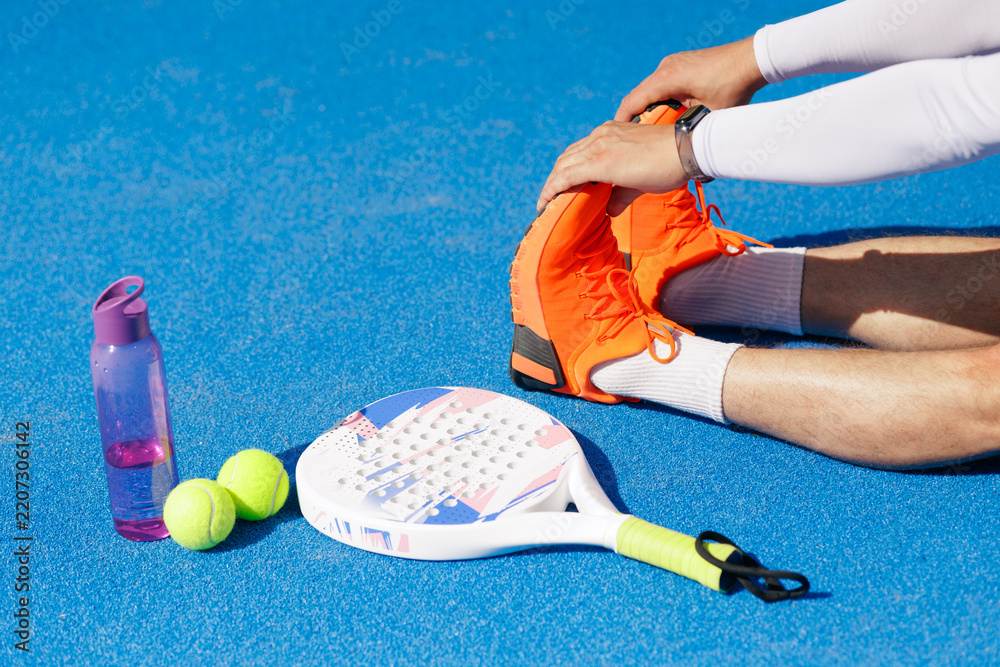 Obraz premium Padel player stretching legs before a match for sports injury prevention
