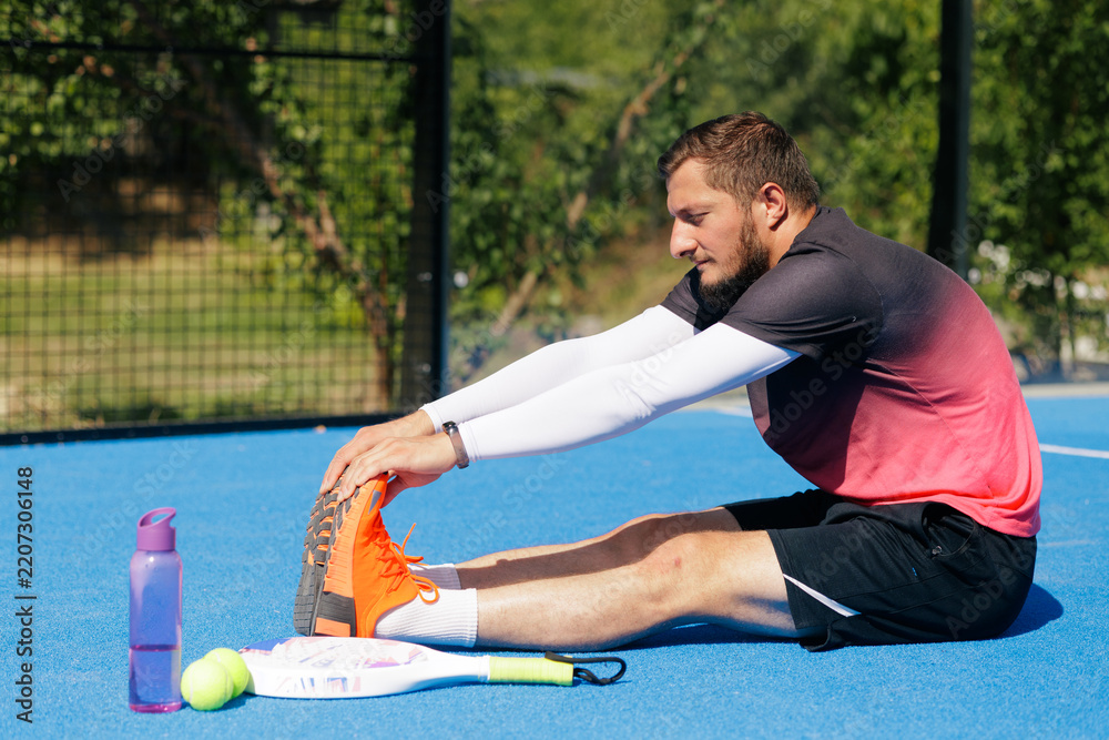 Obraz premium Padel Player Stretching Before Match for Sports Injury Prevention