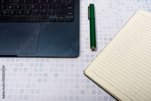 Top view of a laptop keyboard, a notebook, and a pen with copy space.