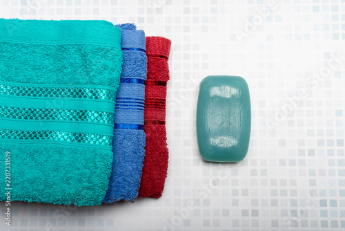 Top view of a stack of colorful towels and a bar of soap.