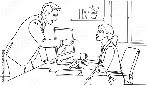 Fotografie A man leans over a desk to point towards a woman working at a computer in an office environment