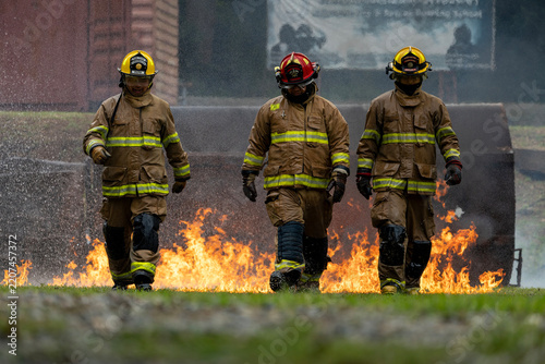 Team of firefighter in fireproof clothe walking out of the burning building full of ash and smoke for fire extinguish risk rescue mission and accident management