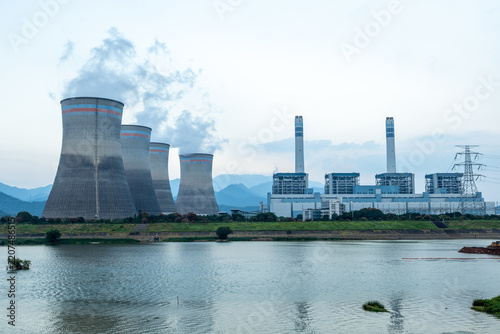 large thermal power plant cooling towers by the river emitting smoke