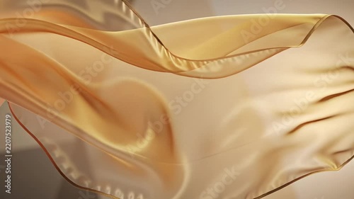 Flowing golden silk fabric waving in gentle motion with soft light and shadows.