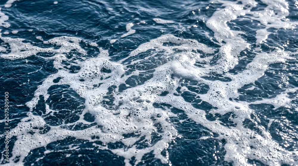 Obraz premium White sea foam and bubbles on dark blue ocean water surface