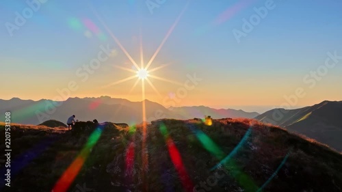 Hiker watching a spectacular mountain sunset with a vibrant sunstar lens flare at Col d'Aubisque in French Pyrenees