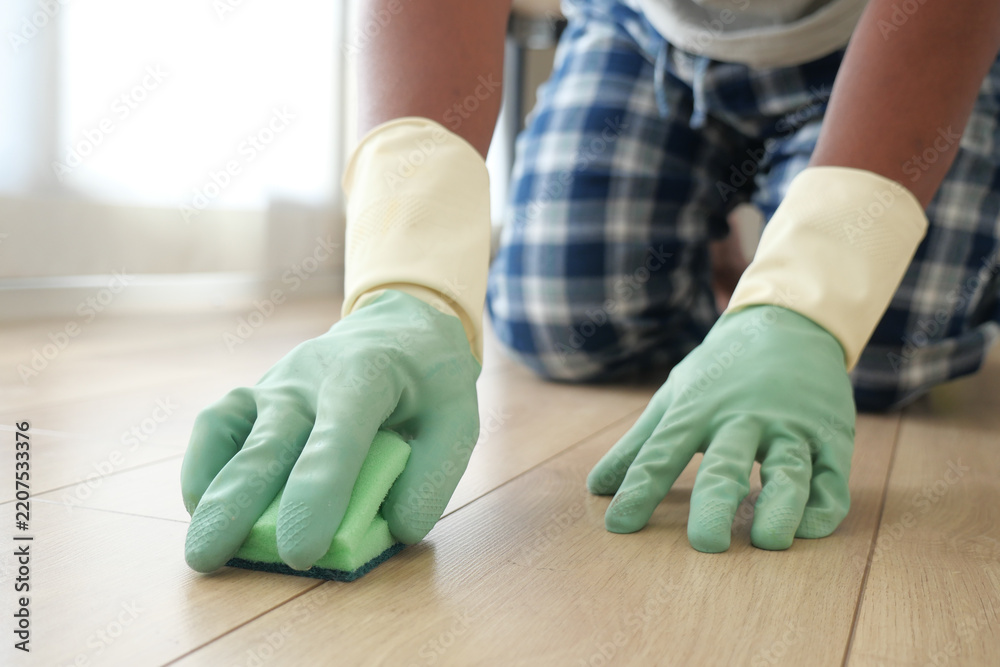 Obraz premium Man cleaning a floor using a sponge while wearing gloves