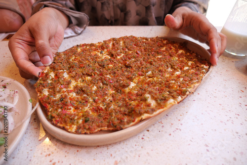 woman is holding a freshly baked lahmacun.