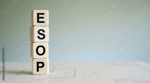 Wooden cubes spelling ESOP stacked vertically on architectural blueprint plans