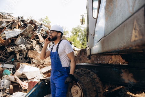 Recycling worker talking on phone at scrapyard