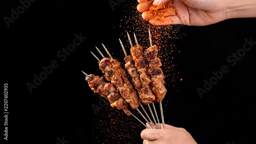 Grilled meat skewers with spice being sprinkled