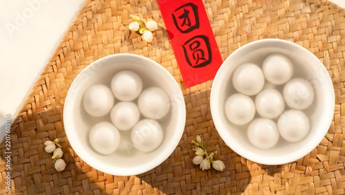 Two bowls of white round dumplings on woven mat