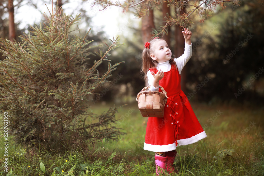 Obraz premium A little girl in a red hat and dresses is walking in the park. Cosplay for the fairytale hero 
