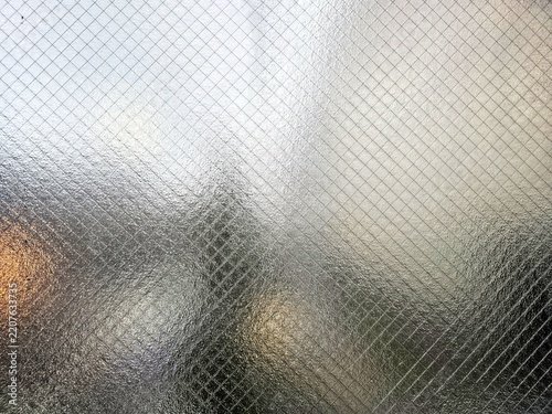 Textured wired security glass window pattern with diagonal wire mesh and soft ambient lighting.