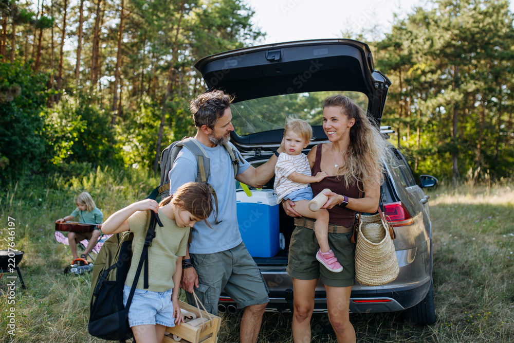 Obraz premium Family unloading luggage from car and setting up a campsite.