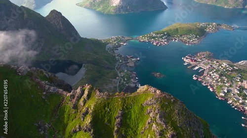 Aerial drone footage over picturesque fishing village with stunning mountains and blue waters.