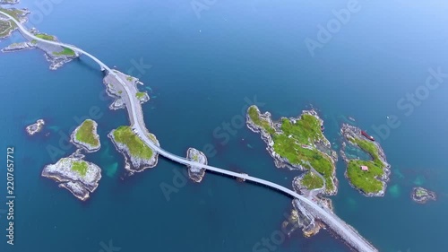 Aerial view of Atlantic ocean road with cars driving across scenic bridges and green rocky islands in Norway.