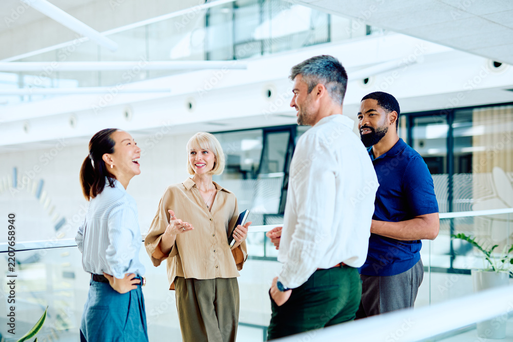 Obraz premium Diverse business professionals having a casual discussion and laughing together during a break in a modern office environment