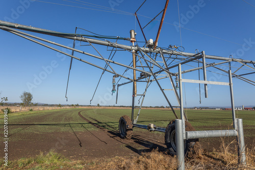 The end piece of a pivot irrigation system showing details of the complexity of a simple machine and the tracks showing its pivoting, circular ability on a crop farm in Queensland, Australia.