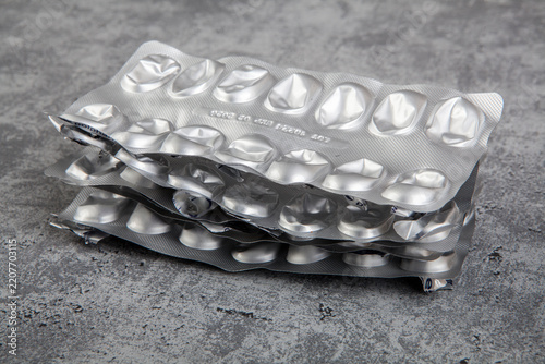 Used and empty aluminum blister packs from tablets and medications. Medical waste. Concept of empty packaging on a gray background.