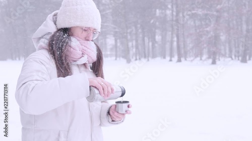 Woman outdoor break. Female serving tea during snowfall. Mindful pause concept.