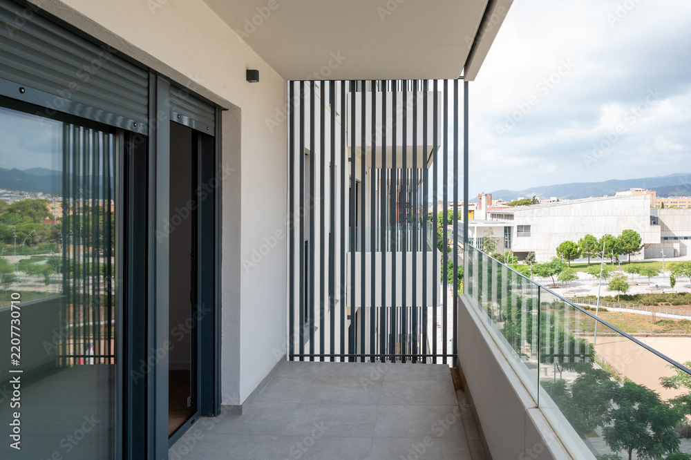 Obraz premium Modern apartment balcony with glass railing and louver privacy screen