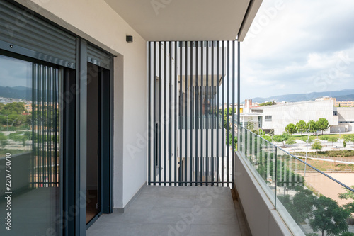 Modern apartment balcony with glass railing and louver privacy screen