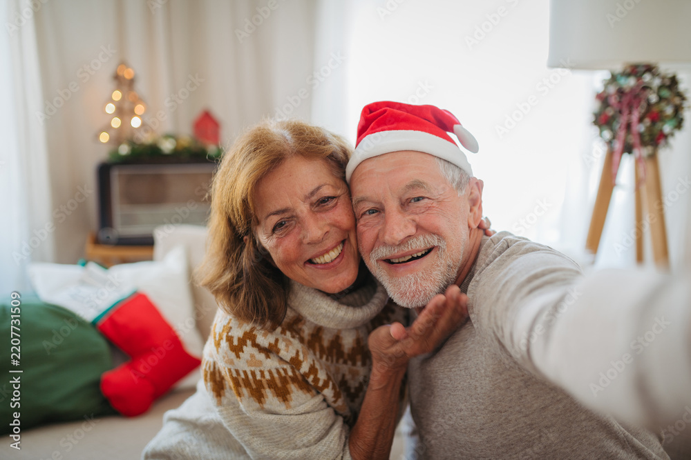 Obraz premium Senior couple making Christmas selfie for family during holidays at home.