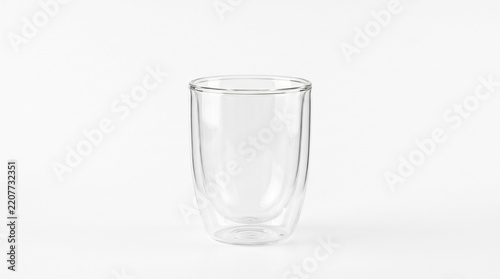 Clear double walled glass cup isolated on a minimalist bright white surface studio photograph
